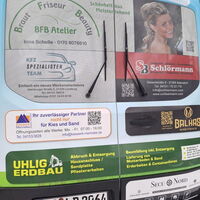 Ein Fahrzeugheck zeigt Werbung für lokale Unternehmen, darunter ein Brautstudio und ein Friseuratelier, mit Kontaktinformationen.