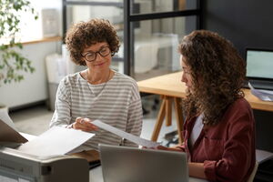 Zwei Frauen im Büro besprechen Dokumente und arbeiten gemeinsam an einem Projekt. | Bildnachweis magnific.com