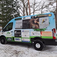 Ein bunt beklebtes Gruppenfahrzeug steht im verschneiten Wichernhaus-Gelände, umgeben von Bäumen.