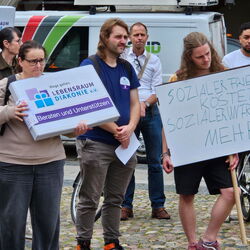 Demonstranten halten Plakate und Schilder bei einer sozialen Protestveranstaltung für Lebensraum Diakonie e.V.