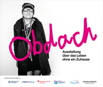 Eine Frau präsentiert die Ausstellung „Obdach“ über das Leben ohne ein Zuhause in Uelzen.