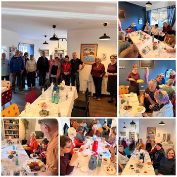Eine Gruppe von Gästen genießt ein gemeinsames Essen in einem gemütlichen Raum mit festlich gedeckten Tischen.