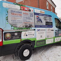 Ein bunt beklebtes Gruppenfahrzeug für das Wichernhaus steht im Schnee vor einem Backsteingebäude.