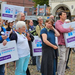 Teilnehmer einer Demonstration halten Schilder für Lebensraum Diakonie, Fokus auf Integration und seelische Gesundheit.