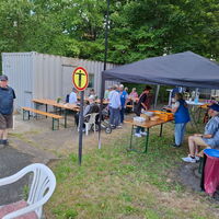 Menschen versammeln sich unter einem Pavillon bei einem lokalen Treffen, um Essen und Gespräche im Freien zu genießen.