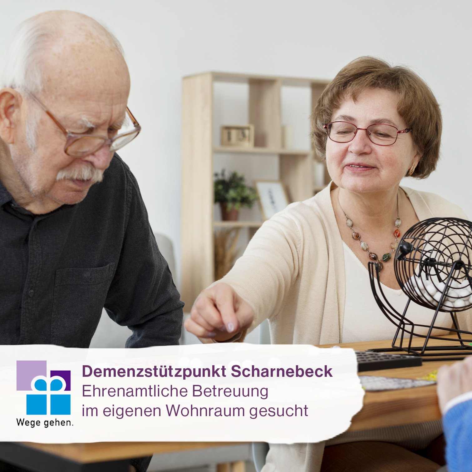Zwei Personen spielen am Tisch, davor Hinweis auf ehrenamtliches Gesuch zur Betreuung in eigenem Wohnraum