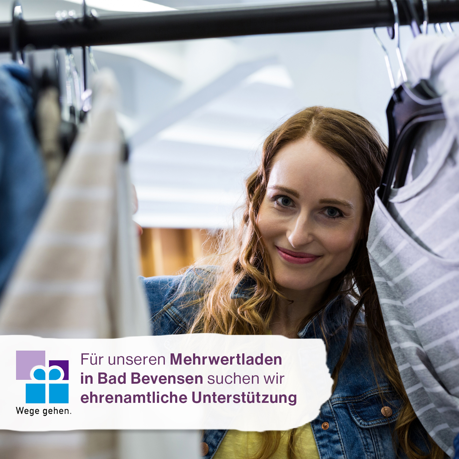 Frau schaut durch Kleiderständer ins Bild